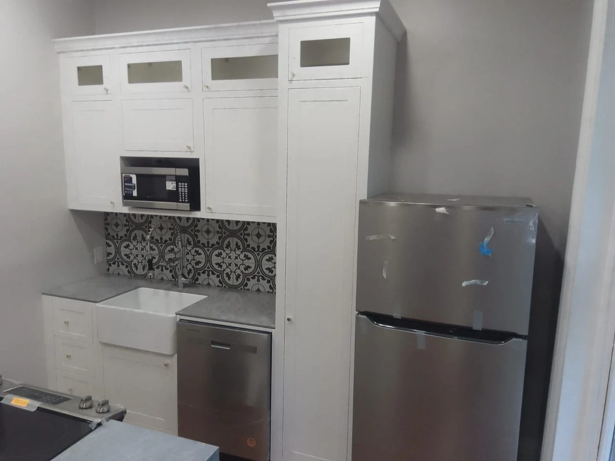 Installed white Shaker-style kitchen cabinet doors with small glazed upper panels and appliance tower
