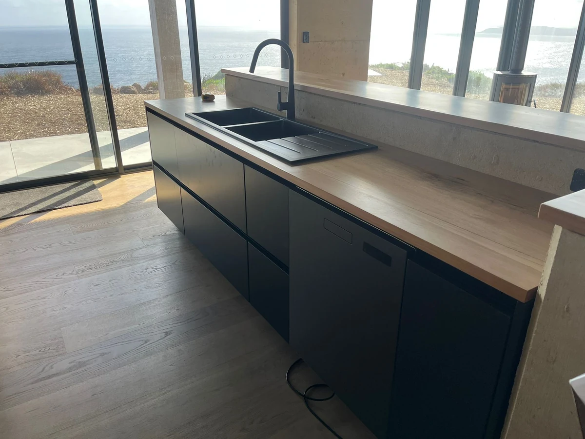 Dark kitchen island cabinetry with integrated sink in a George Group overseas customer installation