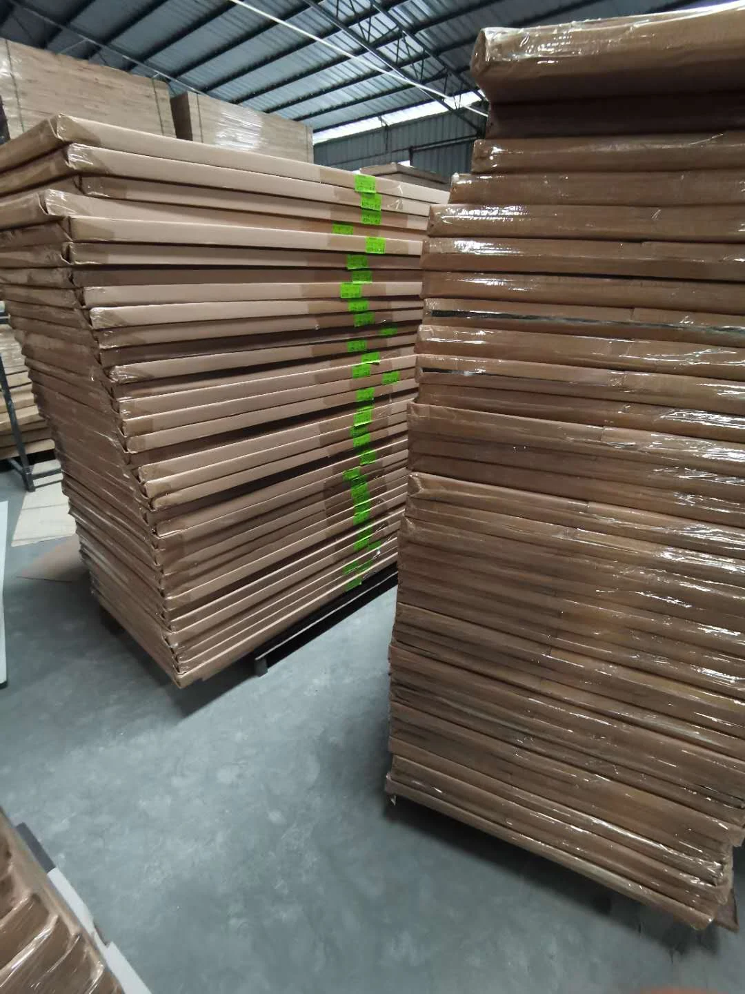 Wrapped wooden panels stacked in a warehouse awaiting dispatch