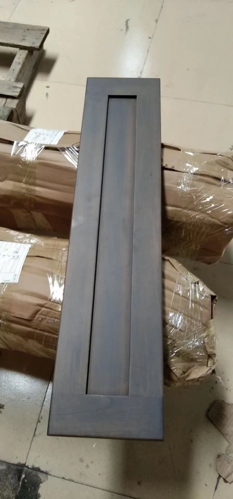 Narrow dark gray stained cabinet door panel photographed on packing material